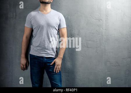 Young healthy man with grey T-shirt on concrete background with copyspace for your text. Picture without model face. Stock Photo