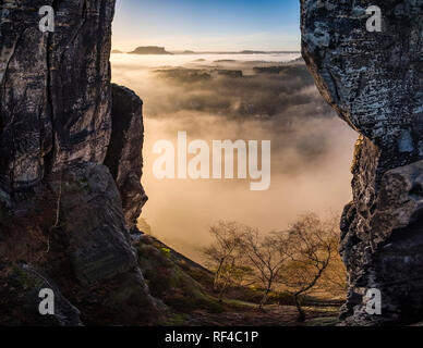 Landscape in the National Park Sächsische Schweiz with rock formations and fog in the river Elbe valley, seen from Bastei bridge at sunrise Stock Photo