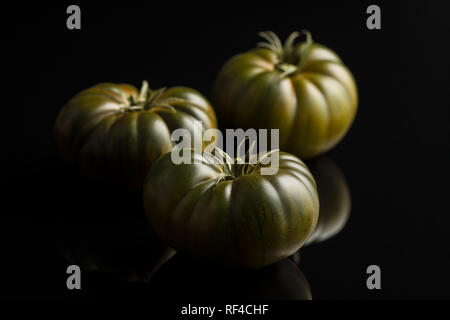 Dark brandywine tomatoes on black background. Stock Photo