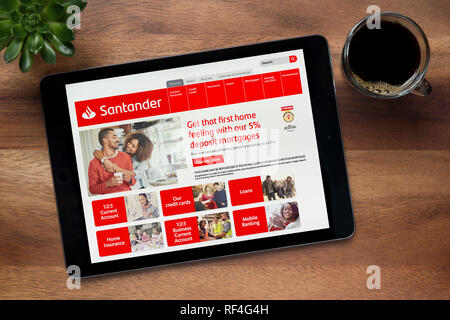 The website of Santander Bank is seen on an iPad tablet, on a wooden table along with an espresso coffee and a house plant (Editorial use only). Stock Photo