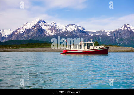 A motorboat motor cruising yacht anchored in a beautiful wilderness bay cove near snow-capped mountains, Glacier Bay National Park, Alaska, USA Stock Photo
