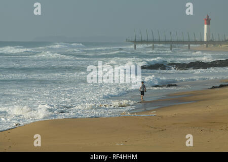 Durban, KwaZulu-Natal, South Africa, single older woman taking early morning walk on Umhlanga Rocks beach Stock Photo