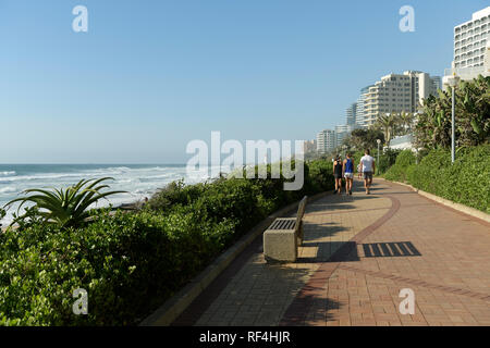 Durban, KwaZulu-Natal, South Africa, group of 3 young people walking on promenade of Umhlanga Rocks beach in morning, landscape Stock Photo