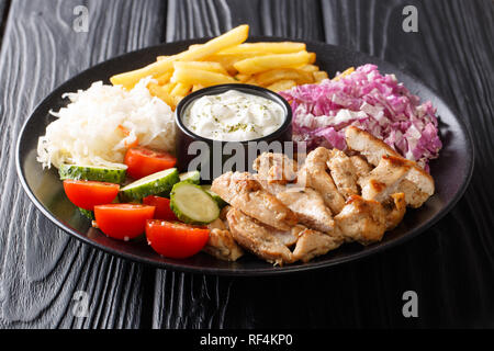 Doner kebab on a plate with french fries, salad and sauce close-up on a wooden table. horizontal Stock Photo