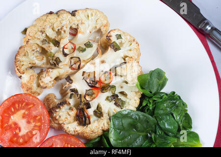 Roasted Cauliflower steak served with wilted Spinach and grilled Tomato Stock Photo