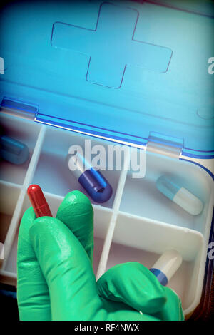 Hand with latex glove supports tablet along with pillbox, conceptual image Stock Photo