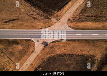 Aerial view of empty road through countryside landscape, abstract top view from drone pov in autumn afternoon Stock Photo