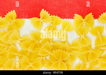 Dry Italian pasta called farfalle on a white-red tablecloth background , beautiful bow tie shape pasta Stock Photo