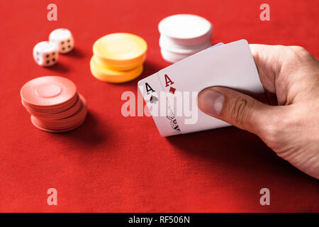 selective focus of man holding playing cards with chips and dices on background Stock Photo
