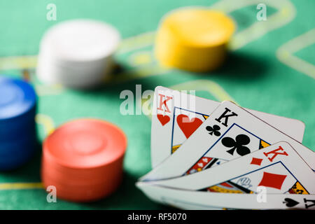 selective focus of playing cards with chips and green poker table on background Stock Photo