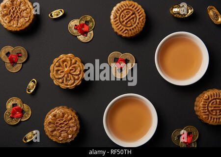 top view of traditional mooncakes, tea cups and feng shui coins isolated on black Stock Photo