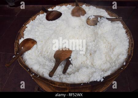 Detail of a big wooden  bucket full of cooked white rice with several wooden spoon lying on it. Stock Photo