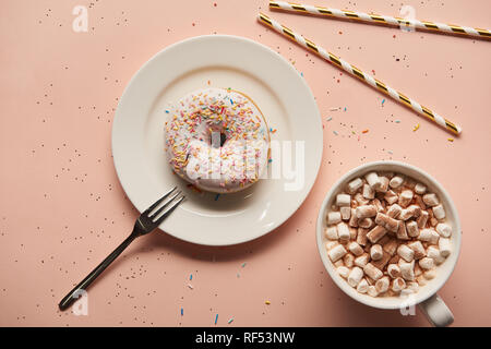 top view of sweet cacao with marshmallows near donut on pink background Stock Photo