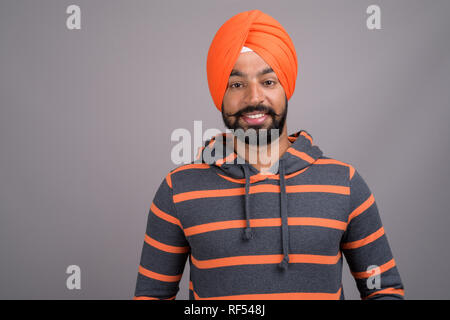 Young handsome Indian Sikh man wearing orange turban