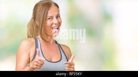 Beautiful middle age woman wearing sport clothes over isolated background pointing fingers to camera with happy and funny face. Good energy and vibes. Stock Photo