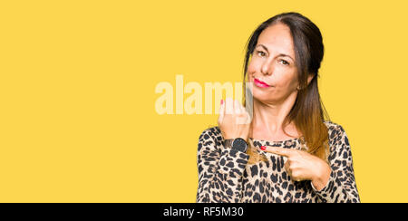 Beautiful middle age woman wearing leopard animal print dress In hurry pointing to watch time, impatience, upset and angry for deadline delay Stock Photo