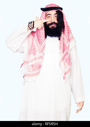 Arabian business man with long hair wearing traditional keffiyeh scarf Pointing with hand finger to face and nose, smiling cheerful Stock Photo