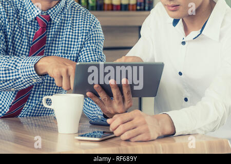 Cropped image businessman sitting at the table with cup of coffee, digital tablet and smart phone, businessman hands typing message on touch screen ta Stock Photo