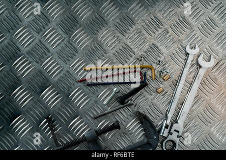 Top view of tools on industrial metal checker plate. Metal checkerplate for anti skid. Nut, bolts, and hex key on metal sheet floor. Silver bump groun Stock Photo