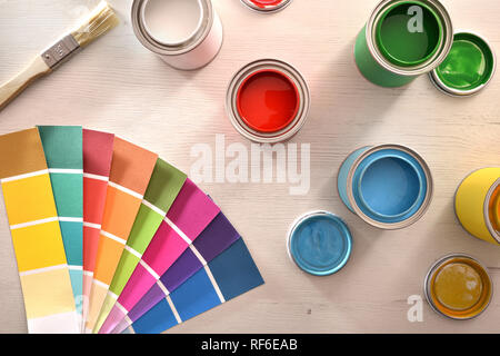 Colorful paint pots open and color palette on white table for renovation of materials. Top view. Horizontal composition. Stock Photo