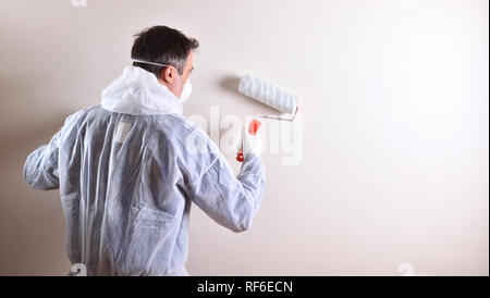 Background with professional painter with working overalls and roller on the back of a white wall. Concept of painter and paint supplies. Horizontal c Stock Photo