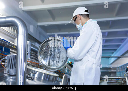 man in a white robe and mask stands near an open can in the shop Stock Photo