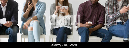 Horizontal image multiracial people sitting in row using electronic devices Stock Photo