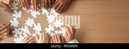 Above panoramic view hands of diverse people assembling jigsaw puzzle Stock Photo