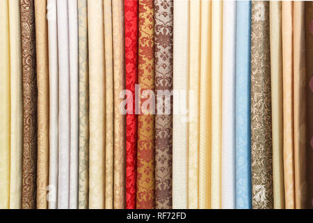 wide selection of different color textile silk fabrics clothes lay in row in drapery store Stock Photo
