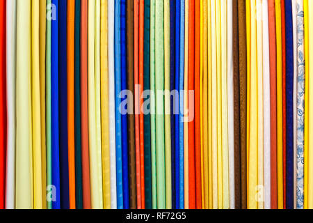 wide selection of different color textile silk fabrics clothes lay in row in drapery store Stock Photo