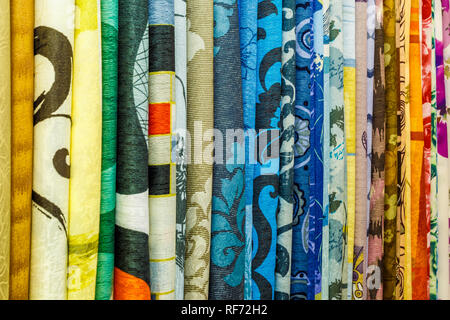 wide selection of different color textile silk fabrics clothes lay in row in drapery store Stock Photo