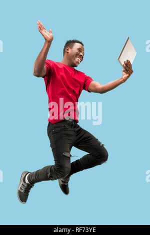 Image of happy excited young african man jumping isolated over yellow background using laptop computer. Stock Photo