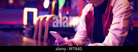 Female bartender using mobile phone at bar counter Stock Photo