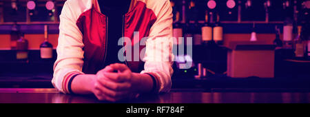 Female bartender standing at bar counter Stock Photo