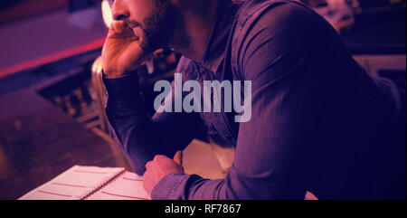 Bartender talking on mobile phone at counter Stock Photo