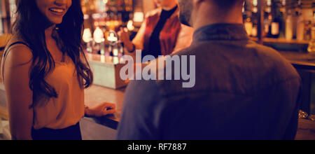 Friends interacting at counter in bar Stock Photo