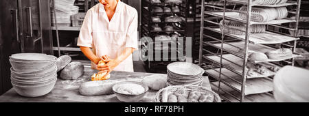 Female baker kneading a dough Stock Photo