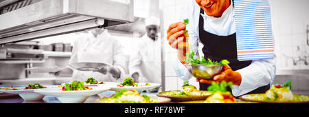 Happy chef garnishing appetizer plates at order station Stock Photo