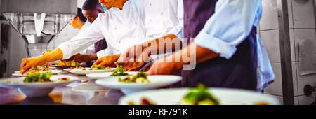 Team of chefs garnishing meal on counter Stock Photo