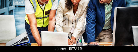 Warehouse managers and worker discussing with laptop Stock Photo