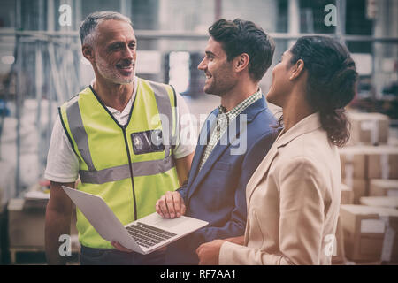 Warehouse managers and worker discussing with laptop Stock Photo