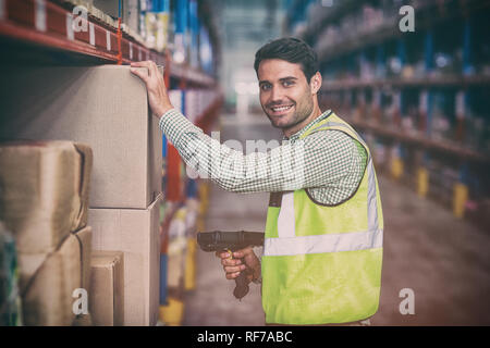 Portrait of smiling warehouse worker scanning box Stock Photo
