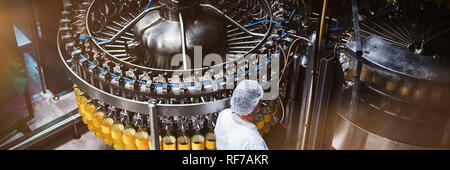 Factory engineer monitoring filled juice bottle on production line Stock Photo