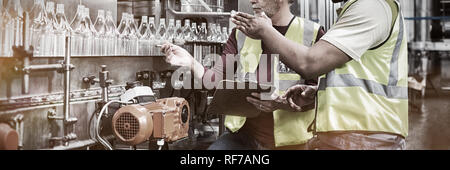 Two factory workers discussing while monitoring drinks production line Stock Photo