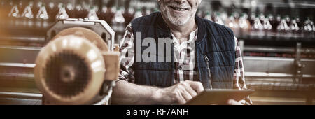Portrait of smiling factory worker standing with a digital tablet in the factory Stock Photo