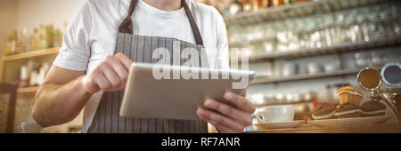 Happy barista using digital tablet at cafe Stock Photo