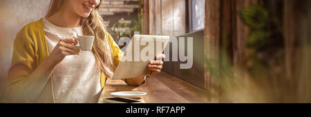 Smiling woman drinking coffee and using tablet Stock Photo