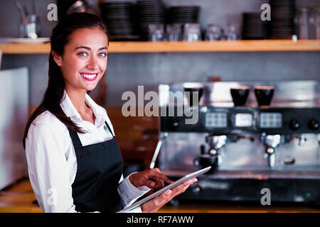 Portrait of smiling waitress using digital tablet Stock Photo