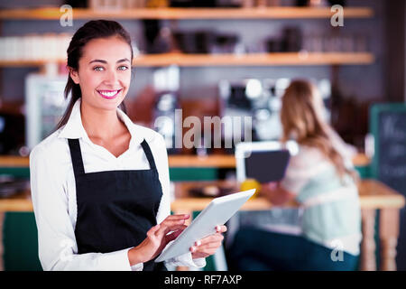 Portrait of smiling waitress using digital tablet Stock Photo