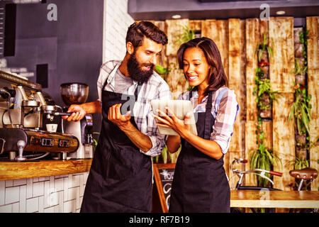 Waitress using a tablet computer and waiter with coffee machine Stock Photo